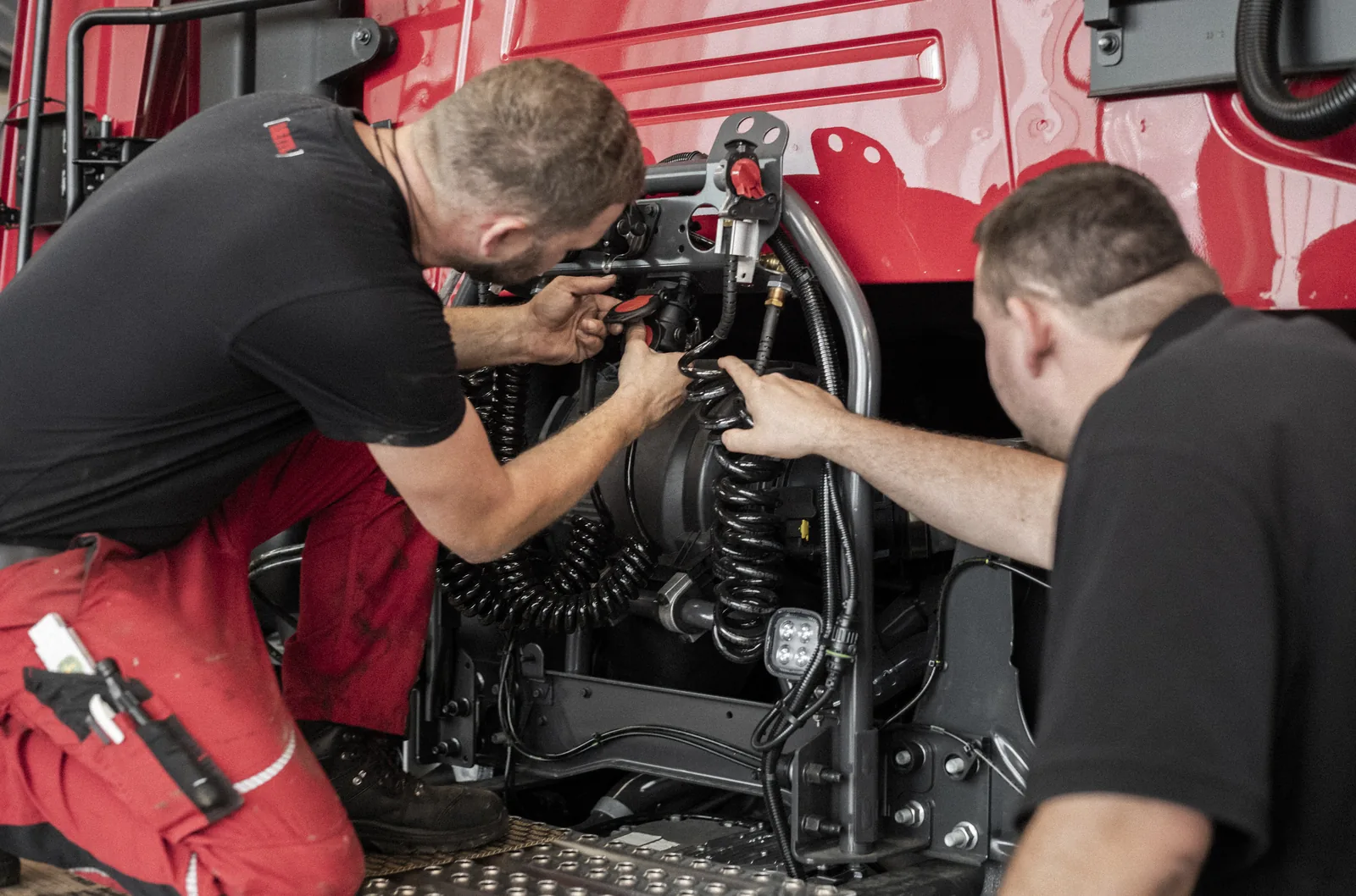 Zwei Techniker arbeiten am Motorraum eines LKW
